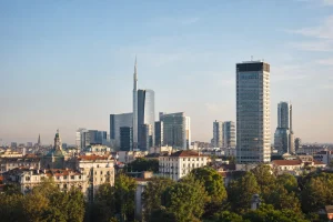 Vista panoramica dell’evoluzione dell’architettura degli uffici a Milano, con grattacieli moderni e distretti direzionali come Porta Nuova sotto un cielo sereno