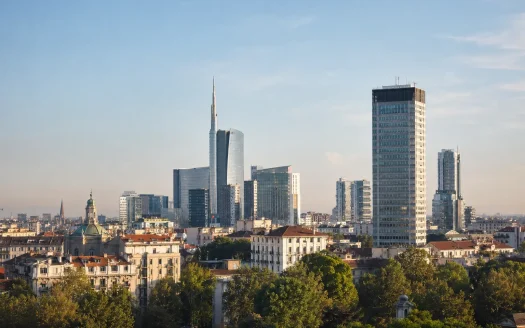 Vista panoramica dell’evoluzione dell’architettura degli uffici a Milano, con grattacieli moderni e distretti direzionali come Porta Nuova sotto un cielo sereno