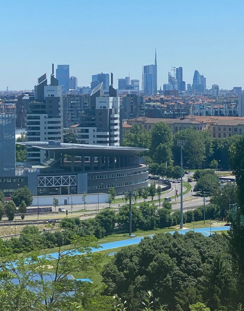 Veduta panoramica del quartiere Rogoredo a Milano con edifici moderni, aree verdi e lo skyline della città sullo sfondo