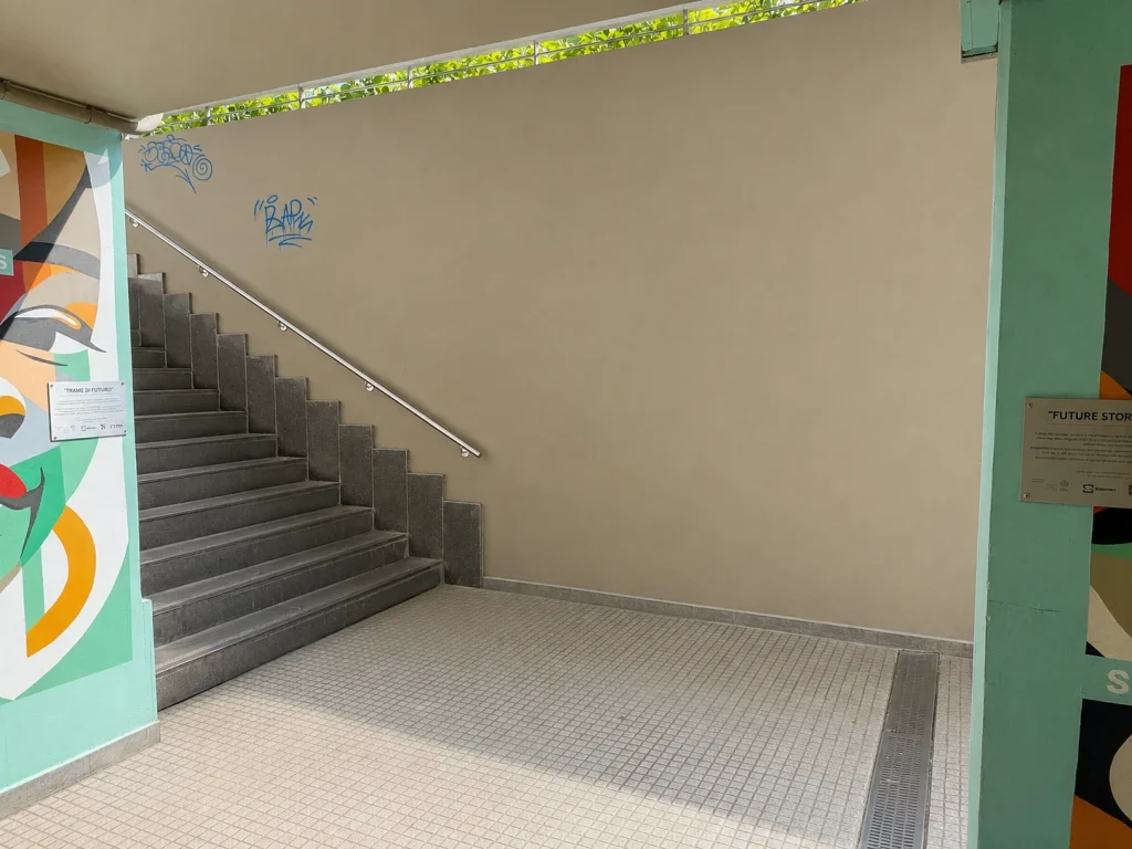 Accesso pedonale con scale e targhe informative presso la stazione di Rogoredo, collegamento chiave per le aziende di Santa Giulia Milano.