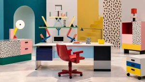 Arredi per ufficio ispirati a Memphis Milano, con scrivania, sedia rossa, libreria geometrica e mobili colorati.